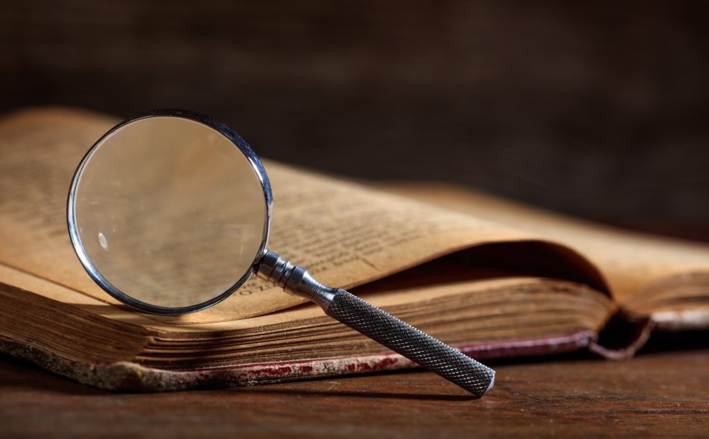 Vintage book and magnifying glass on wooden desk