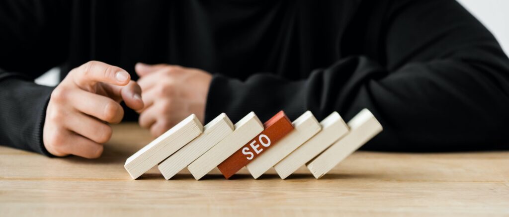 panoramic shot of seo manager pointing with finger at wooden rectangles with lettering seo, what is topical authority, topical authority in SEO, how do I get topical authority