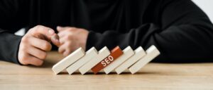 panoramic shot of seo manager pointing with finger at wooden rectangles with lettering seo, what is topical authority, topical authority in SEO, how do I get topical authority