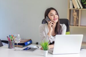 Happy beautiful Asian businesswoman talking on the phone the laptop is placed on the office desk. Brand Image, Press Releases, Public Relations, Corporate Reputation, Brand Awareness, Customer Perception