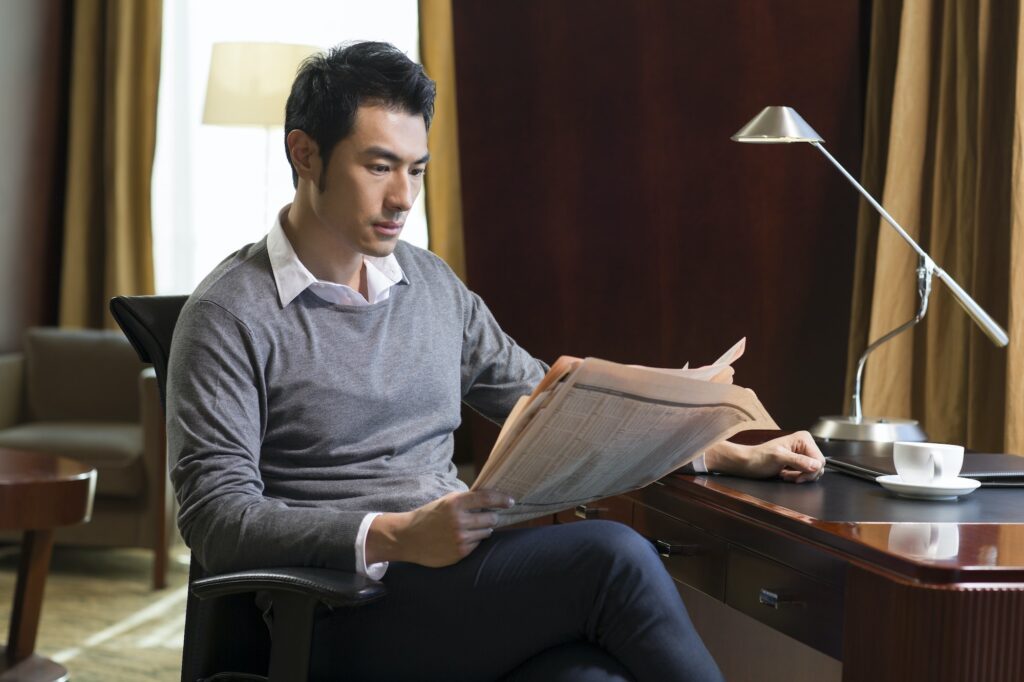 Young businessman reading newspaper in study, how to use press releases for SEO