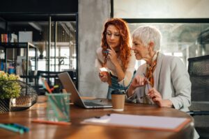 Two female marketing experts discussing strategy and ideas at office.