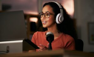 Woman, headphones with radio DJ or podcast, public relations journalist and live broadcast at night